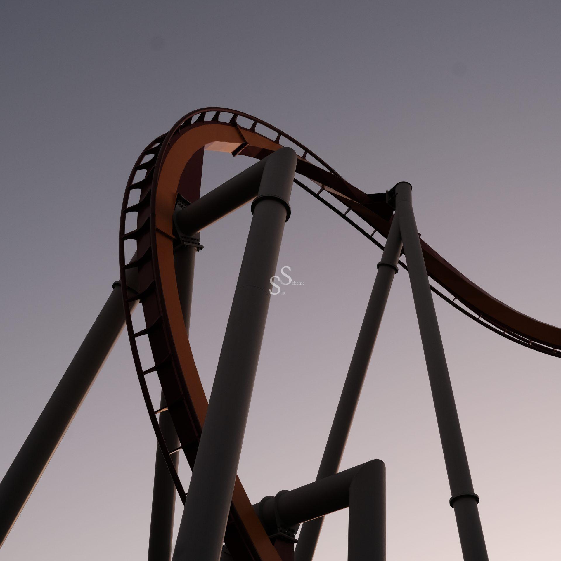 A close-up view of a steel roller coaster track with loops and tall support beams, photographed against a clear, dusky sky.